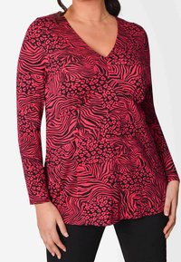 Maglietta a maniche lunghe con scollo a V, caratterizzata da un mix di fantasia zebra e leopardo in rosa e nero, realizzata in un tessuto morbido.