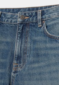 Ceinture de jean en denim bleu avec fermeture à bouton, passant de ceinture, surpiqûres orange visibles et détail de poche avant.