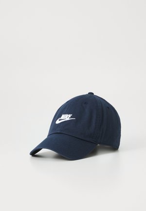 Marineblå bomuldske med en buet skygge. Har et hvidt broderet Nike-logo på fronten. Seks ventilationshuller på toppen.