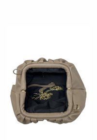 Bežová kabelka z umělé kůže s zaobleným, sbíraným designem. Interiér má černou podšívku a zlaté řetízkové detaily. Viditelné vnitřní kapsy.