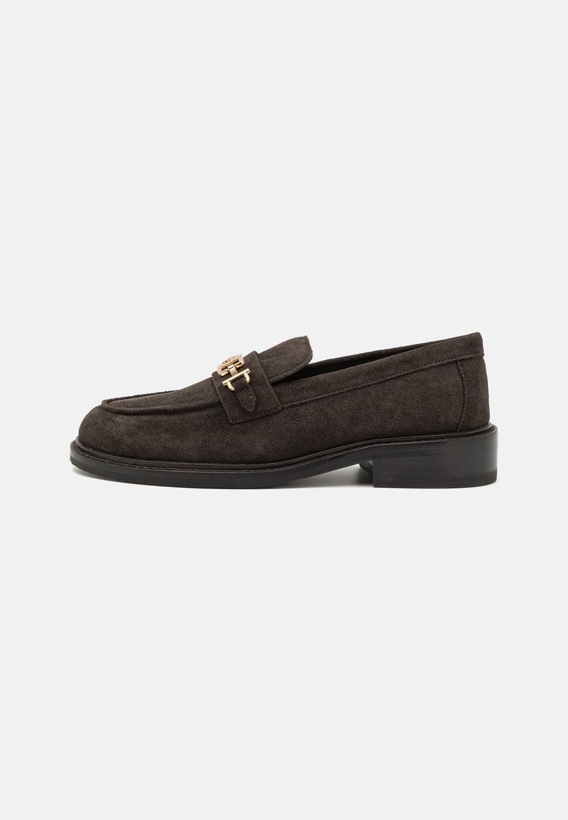 Mocassin en daim brun foncé avec une boucle dorée décorative, bout rond, petit talon empilé noir et texture lisse.