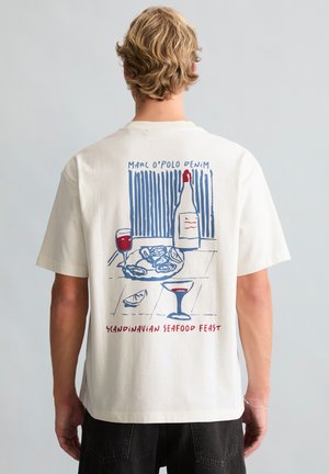 Blond persoon draagt wit overhemd met afbeelding van wijnfles, twee wijnglazen, schaal met zeevruchten en de tekst "Scandinavian Seafood Feast" op de rug.