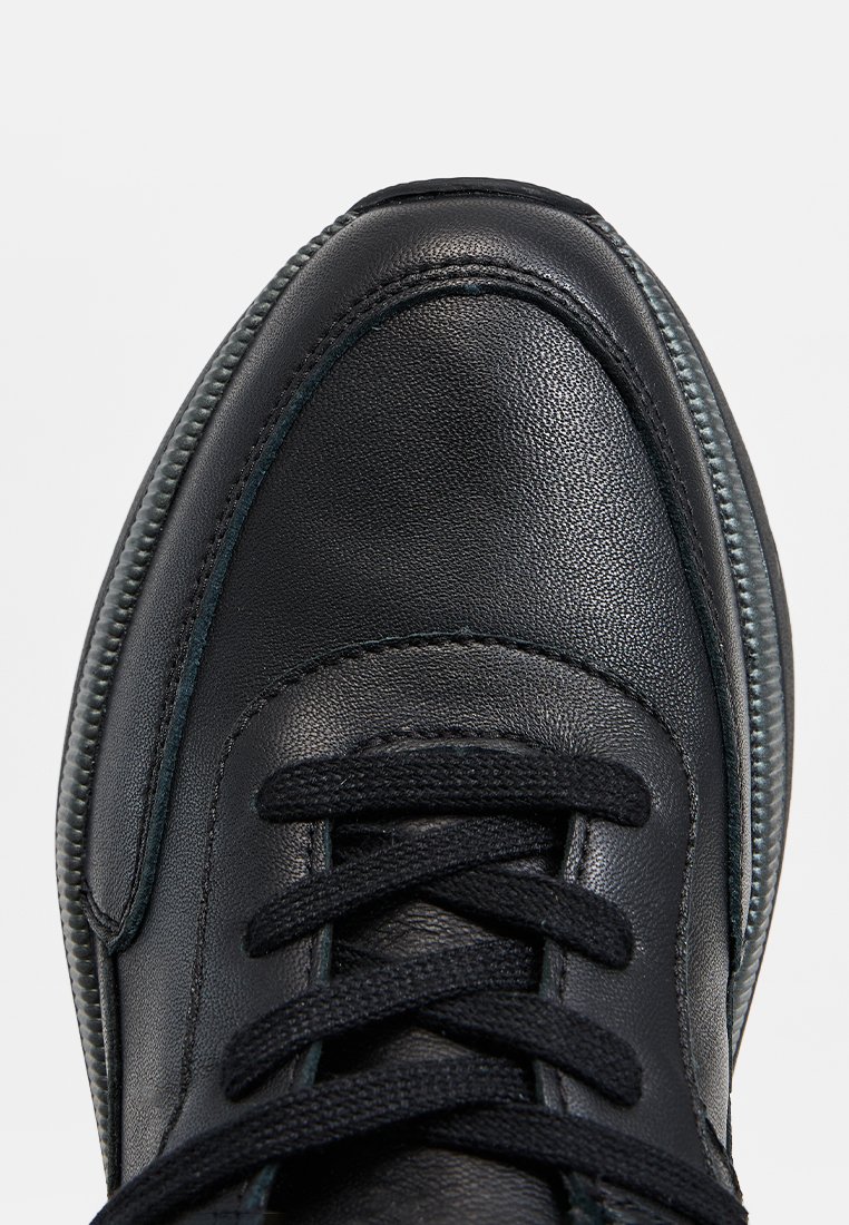 Czarne skórzane tenisówki o gładkiej fakturze, z czarnymi sznurowadłami, zaokrąglonym noskiem i kontrastowym przeszyciem wzdłuż podeszwy.