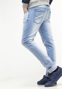 Ljusblå denimjeans med slim fit, fem fickor, blekt mönster och broderad detalj på bakfickan. Matchas med mörkblå sneakers.