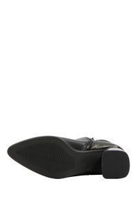 Botine negre din piele, cu talpă texturată, fermoar pe lateral și toc mic, având un design al upper-ului neted și vârf ascuțit.