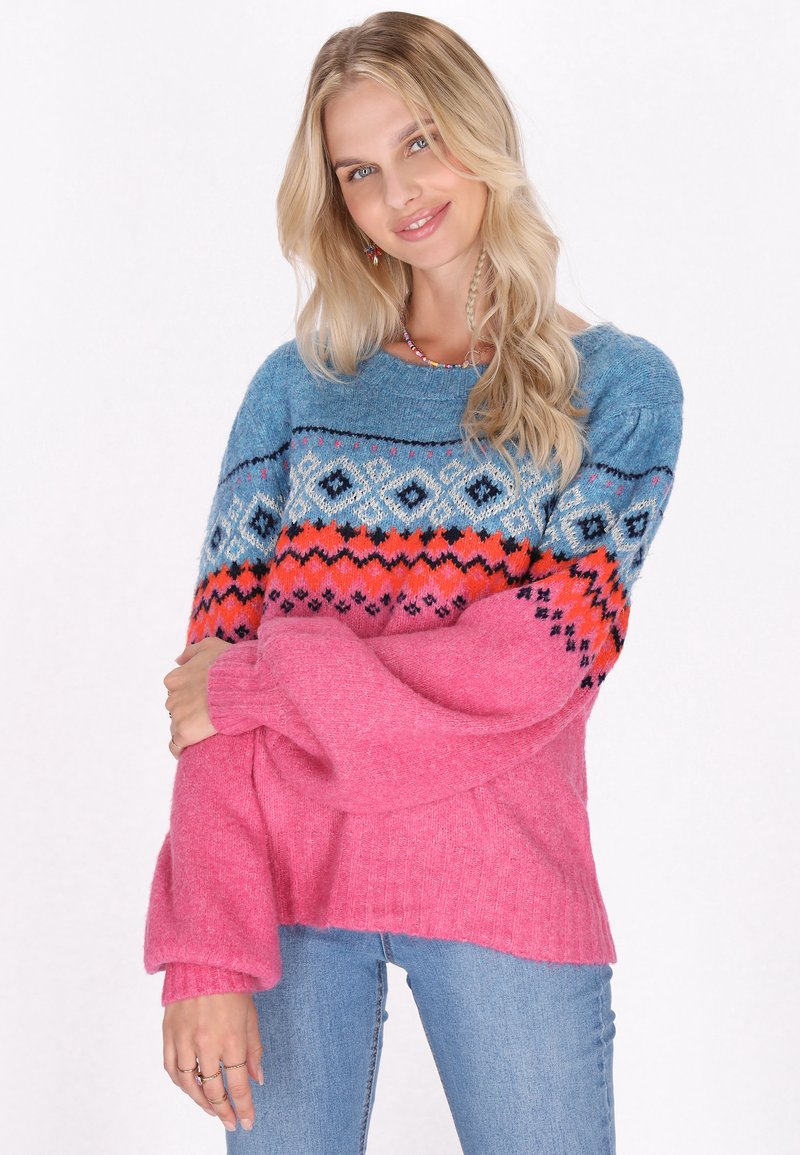 Strickpullover mit einem blauen Oberteil, das geometrische Muster in Orange und Pink aufweist, sowie pinken Rippärmel und Saum, aus weichem Material gefertigt.
