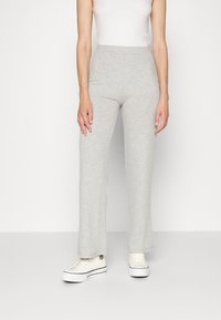 Ljust grå, ribbad, stickad byxor med vida ben och hög midja, i kombination med vita sneakers. Slät struktur och en avslappnad design.