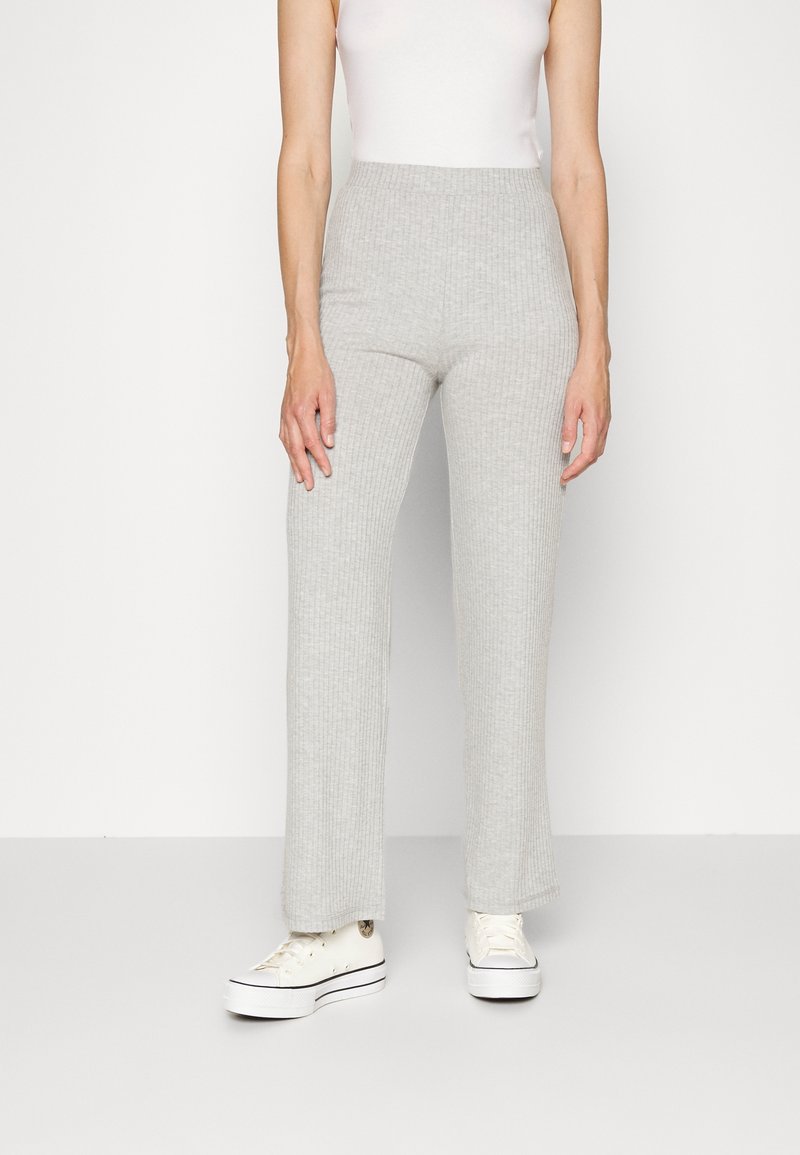Ljust grå, ribbad, stickad byxor med vida ben och hög midja, i kombination med vita sneakers. Slät struktur och en avslappnad design.