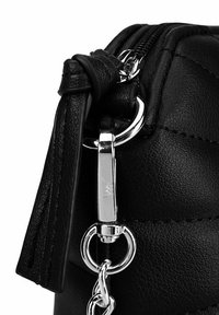 Černá kožená crossbody taška s prošívaným designem, stříbrnými doplňky, zipovým uzávěrem a strukturovaným povrchem. Obsahuje dekorativní třásně.