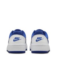 Sapatos Nike com sola e calcanhar brancos, parte superior sintética azul, colarinho almofadado e logótipo Nike azul na parte de trás. Design de cano baixo.