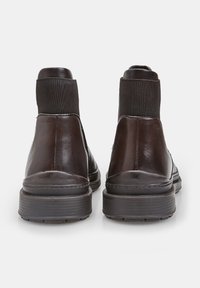 Stivali alla caviglia in pelle marrone con pannelli laterali elasticizzati, punta rotonda e suole in gomma testurizzata, caratterizzati da un design elegante e minimalista.