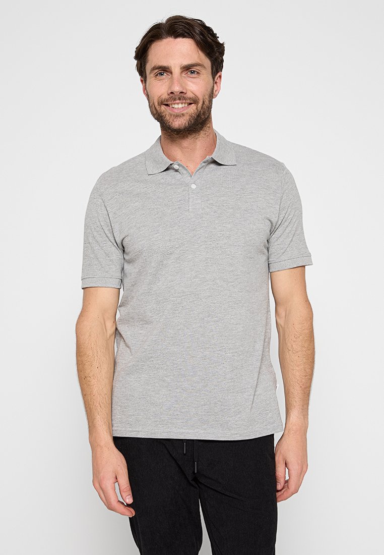 Polo shirt en coton gris avec un col classique, patte de boutonnage à trois boutons et manches courtes, associé à un pantalon texturé sombre.