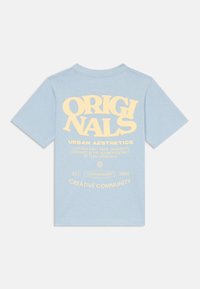 Světle modré bavlněné tričko s krátkými rukávy. Velký žlutý text na zádech zní "ORIGINALS URBAN AESTHETICS" a níže jsou uvedeny další detaily.
