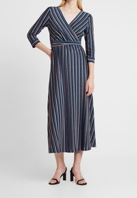 Robe midi rayée en bleu marine, avec un col en V, des manches trois-quarts et une taille ceinturée. Présente des rayures verticales de différentes couleurs.