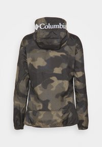 Kamouflage-mönstrad jacka med huva som har vita "Columbia"-logon över baksidan av huvan.