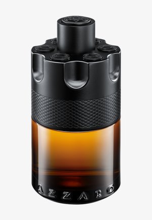 Amberfarvet glas parfume flaske med sort tekstureret låg designet som en revolvercylinder, mærket "Azzaro" ved bunden.