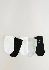 Cinq paires de chaussettes de cheville : deux blanches avec des visages souriants verts, une noire avec un visage souriant bleu, une grise avec un visage souriant vert, une noire. Mélange de coton.