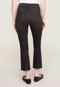 Höga svarta jeans med zebramönster, avkortad benlängd och två bakfickor, tillverkade av en mjuk bomullsmix.