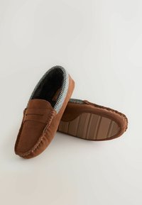 Ruskeat mokkanahkaiset tohvelit, joissa on ruudullinen kangasvuori, mokkasiinityylinen ompelu ja kumipohjat, joissa on reunassa raidallinen kuvio.