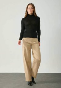 Pulover negru cu guler înalt, croială mulată; pantaloni bej cu picior larg; cizme negre cu toc; fundal simplu; texturi netede; design elegant.