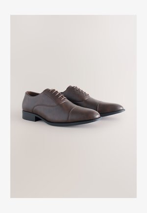 Braune Lederschuhe mit glatter Textur, Schnürdesign, spitzer Zehe und einer kontrastierenden schwarzen Gummisohle. Klassischer und vielseitiger Stil.