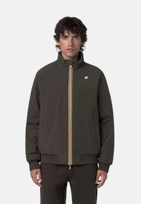 Giacca bomber marrone con polsini a coste, colletto alto e zip frontale con strisce gialle, bianche e rosse. Logo sul petto.