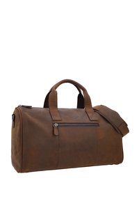 Bruine leren reisttas met twee handvatten bovenaan, afneembare schouderriem en een voorvak met rits, met een gladde textuur en minimalistisch ontwerp.