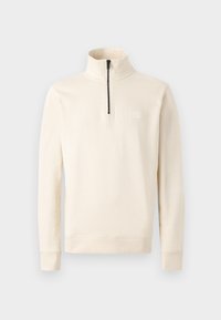 Beige half-zip pullover made of soft fabric, featuring a stand-up collar and a small logo patch on the chest. Long sleeves with fitted cuffs.