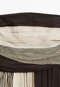 Gestaffelter Stoff in neutralen Tönen von Beige und Braun, mit horizontalen Streifen in unterschiedlichen Breiten und Texturen, die ein sanftes Erscheinungsbild erzeugen.