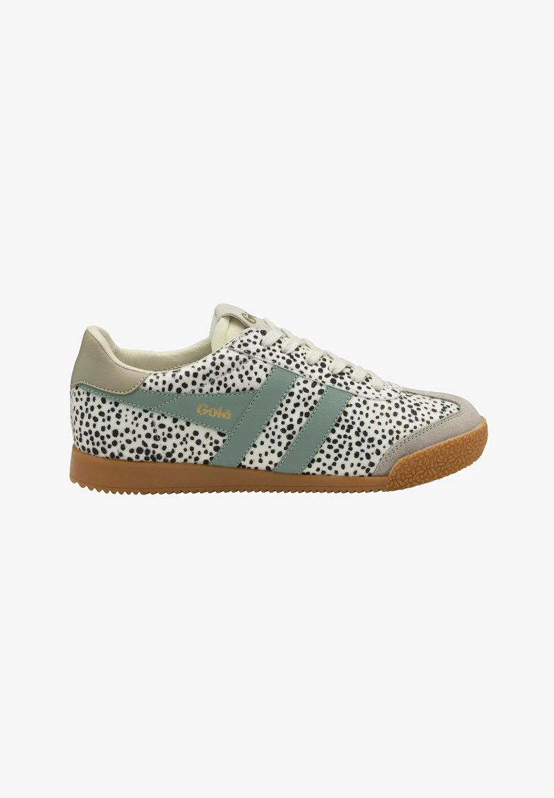 Sneaker basso con tessuto bianco e nero maculato, dettagli beige, strisce laterali verdi e suola marrone strutturata.