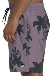 Costumi da bagno viola con motivo floreale nero, vita elastica, tasche laterali e cordoncino. Il materiale sembra leggero e testurizzato.