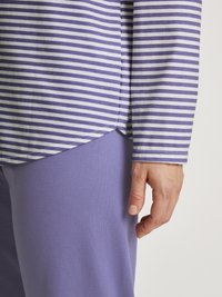 Gestreiftes Langarmshirt in Helllila und Weiß, kombiniert mit einfarbigen lila Hosen, die einen entspannten Schnitt und eine weiche Baumwolltextur präsentieren.