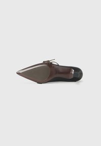 Chaussure à talon haut à bout pointu avec un dessus noir et une semelle brune. Dotée d'une légère courbure et d'une sangle à l'avant. Texture lisse.