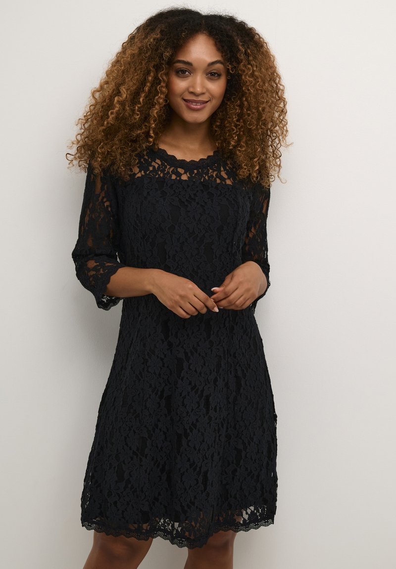 Abito in pizzo nero con maniche a tre quarti, motivo floreale, scollatura a scallop e orlo scallop. Tessuto leggero e textured con una silhouette aderente.