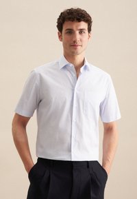 Camicetta a maniche corte, con bottoni, di colore azzurro chiaro con sottili righe, dotata di taschino sul petto, colletto strutturato e texture del tessuto liscia.