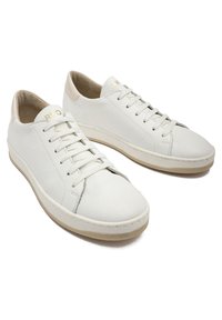 Białe skórzane sneakersy z gładką teksturą, okrągłym czubkiem, kontrastującą beżową podeszwą oraz minimalistycznym designem z sześcioma oczkami i detalem z logo.