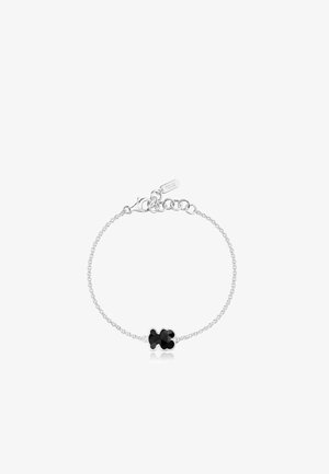 Braccialetto in argento con al centro una pietra nera a forma di quadrifoglio, con un design di collegamento delicato e un piccolo TAG inciso con "TOUS".