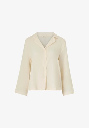 Camisa de botón de manga larga en un color crema pálido, con una tela texturizada, cuello de chal y cinco botones al frente. El dobladillo es recto.