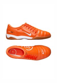 Chaussures Nike Total90 III en orange vif, dotées d'une tige en cuir lisse, de détails texturés et d'un swoosh blanc sur le côté. Semelle en caoutchouc brun.