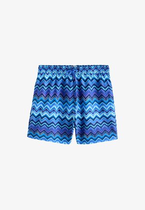 Primo piano della zona centrale di una persona che indossa un costume da bagno con motivo a zigzag blu e viola con un laccio blu annodato.