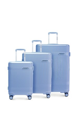 Drie lichtblauwe koffers met harde schaal in kleine, middelgrote en grote maat, elk voorzien van een telescopisch handvat en vier wielen, naast elkaar geplaatst.