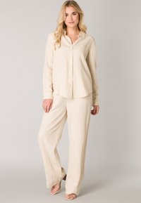 Beige linnen shirt en wijde broek set. Shirt met knoopsluiting aan de voorkant, kraag en een enkele borstzak; zachte, gestructureerde stof.