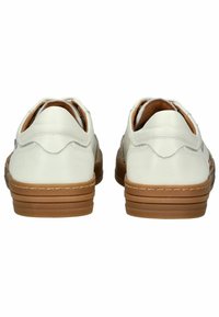 Scarpe bianche in pelle caratterizzate da un design arrotondato, suola in gomma color cammello e dettagli scallopati sul tallone, con cuciture visibili.