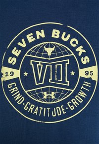Granatowa koszulka z żółtym nadrukiem graficznym z napisem "SEVEN BUCKS", wzorem globusa oraz hasłem "GRIND. GRATITUDE. GROWTH." Wygląd teksturowany.