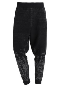 Schwarze Jogginghosen aus strukturiertem Strickstoff, mit einem elastischen schwarzen Bund und einem Farbverlaufsmuster zu den Säumen hin. Stilvoll und bequem.
