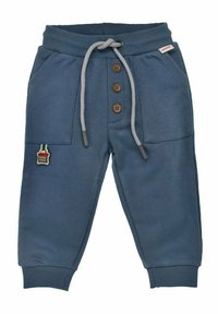 Pantaloni della tuta blu realizzati in tessuto morbido, con vita elasticizzata, cordino, dettagli con bottoni e una piccola patch decorativa.