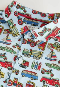 Camicia azzurra a maniche corte con un vivace motivo di veicoli, tra cui auto, camion e barche, con colletto a bottoni e bottoni bianchi.