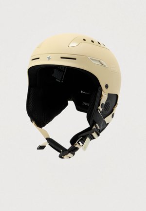 Ski prilba v mat beige farbe s čiernym vnútorným polstrovaním. Má nastaviteľné remene, ventilačné otvory a logo značky na boku.