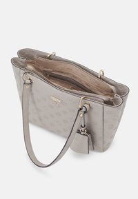 Sac à main gris Guess avec motif logo texturé, ferrures dorées, doubles poignées et ouverture supérieure laissant apparaître des compartiments intérieurs zippés et une doublure siglée.