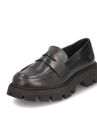Schwarze Lederloafers mit einem erhöhten Riemendetail, grober strukturiertem Absatz und abgerundetem Zehenbereich, mit einem dezenten Logo an der Seite.